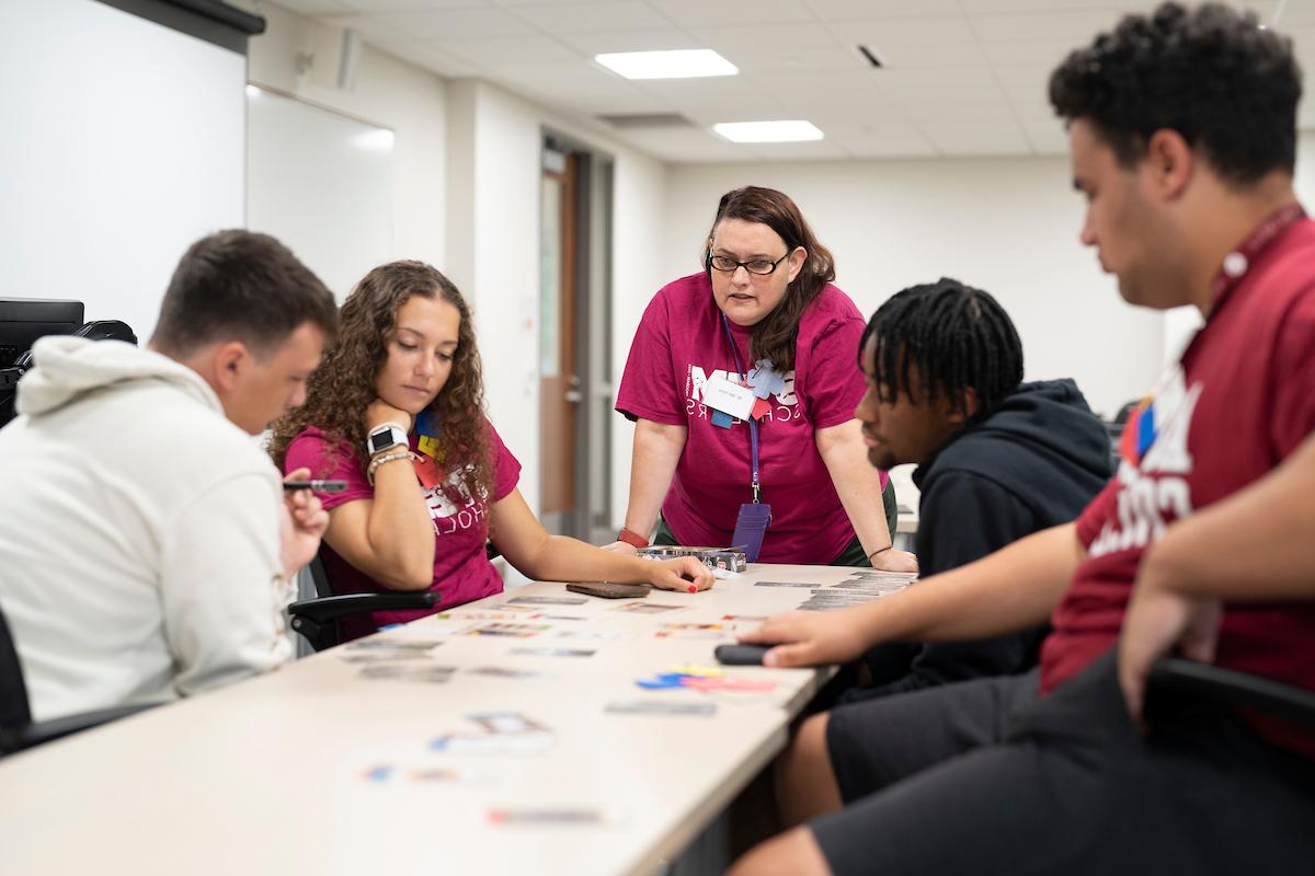 Students and professor looking intently at cards on a table